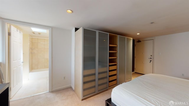 bedroom featuring light colored carpet and ensuite bath