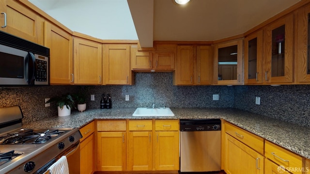 kitchen with appliances with stainless steel finishes, decorative backsplash, stone counters, and sink