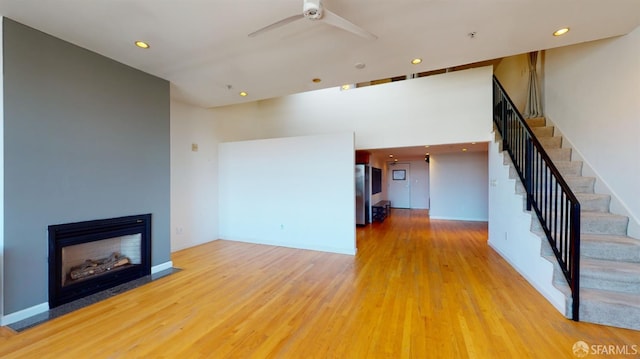 unfurnished living room with a high ceiling, hardwood / wood-style floors, and ceiling fan