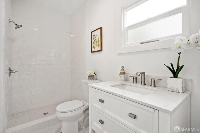 bathroom with vanity, toilet, and a tile shower