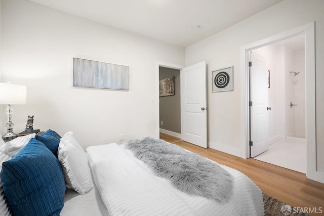 bedroom featuring light wood-type flooring and ensuite bath