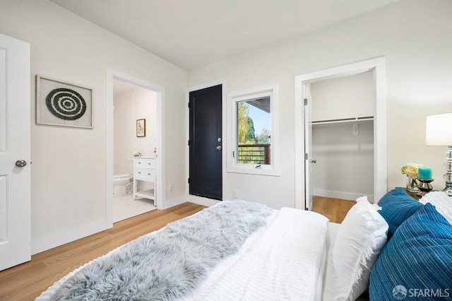 bedroom with connected bathroom, a spacious closet, a closet, and hardwood / wood-style flooring