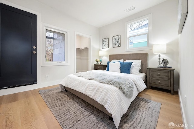 bedroom featuring a spacious closet, light hardwood / wood-style flooring, and a closet