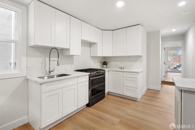 kitchen featuring light wood-type flooring, white cabinetry, sink, and gas range