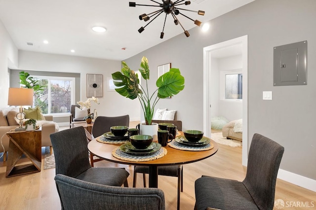 dining room with electric panel, light hardwood / wood-style flooring, and a notable chandelier