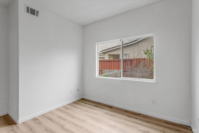 empty room featuring wood finished floors, visible vents, and baseboards