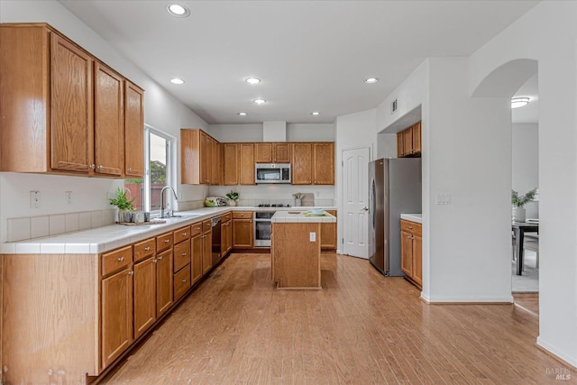 kitchen featuring light wood-style flooring, a kitchen island, appliances with stainless steel finishes, a sink, and recessed lighting