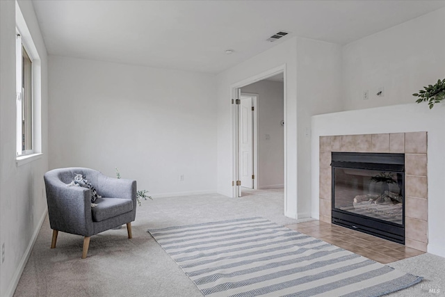 living area featuring baseboards, visible vents, carpet flooring, and a tile fireplace