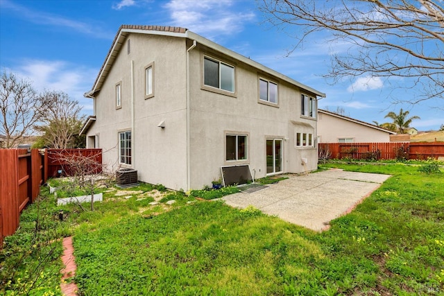 rear view of house with stucco siding, a fenced backyard, a patio area, and a yard