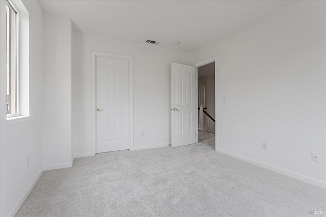 unfurnished bedroom with carpet, visible vents, and baseboards