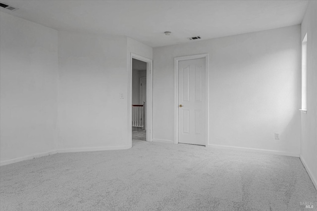 empty room with carpet floors, visible vents, and baseboards