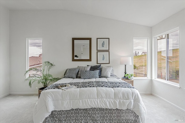 carpeted bedroom with lofted ceiling and baseboards