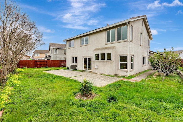 rear view of house with a patio, a lawn, fence, and stucco siding