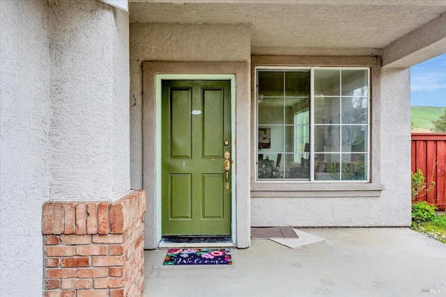 doorway to property featuring fence and stucco siding