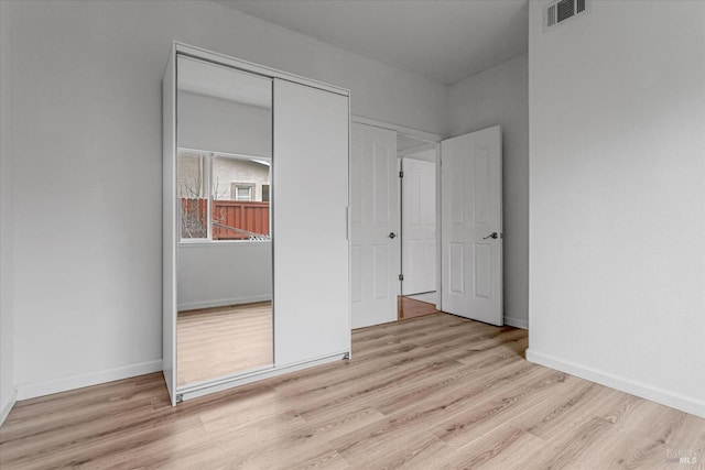 unfurnished bedroom with wood finished floors, visible vents, and baseboards