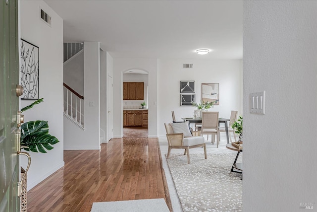 entrance foyer with arched walkways, stairs, wood finished floors, and visible vents