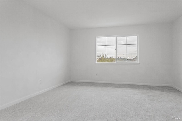 spare room featuring carpet and baseboards