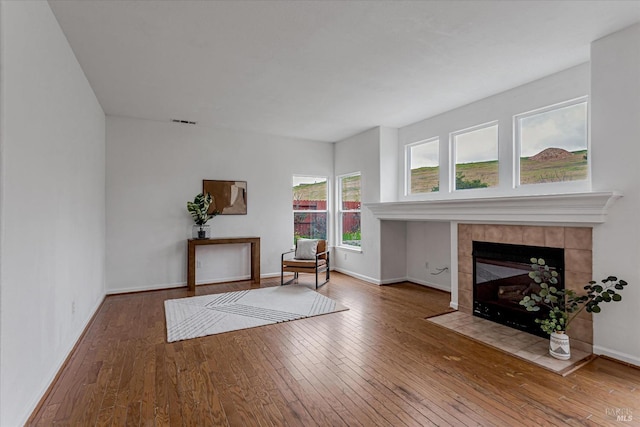 living area with visible vents, a fireplace, baseboards, and hardwood / wood-style floors