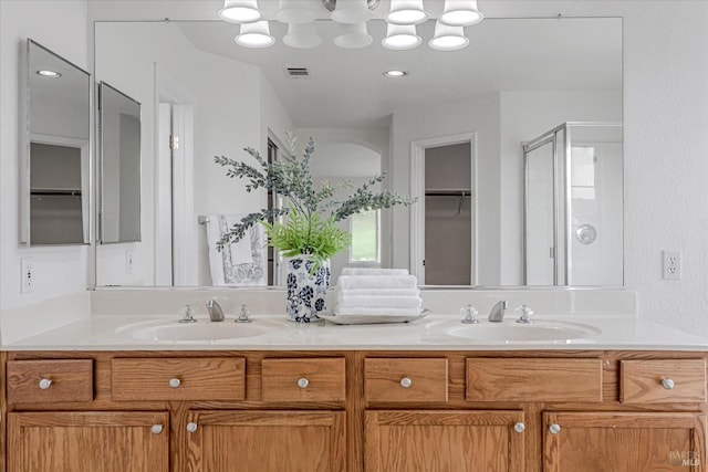 bathroom with a stall shower, a sink, and double vanity