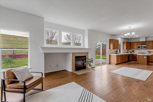 living room with an inviting chandelier, baseboards, light wood finished floors, and a tiled fireplace