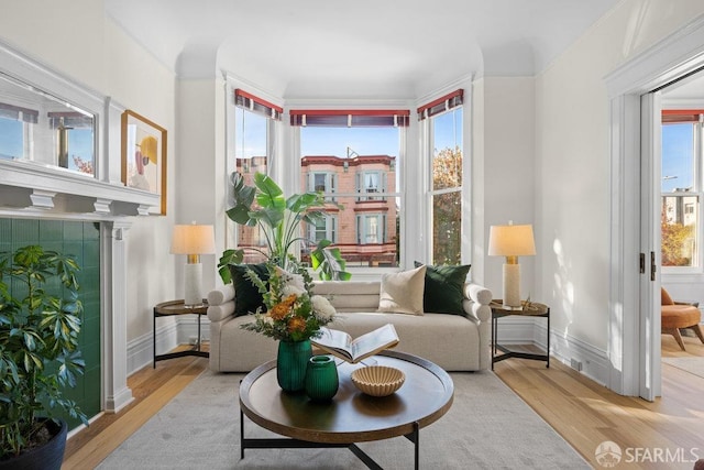 living area with crown molding and light hardwood / wood-style flooring