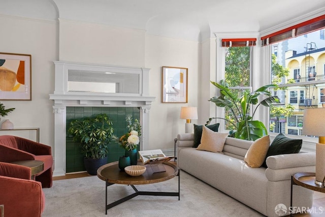 sitting room featuring a tile fireplace, light hardwood / wood-style flooring, and ornamental molding