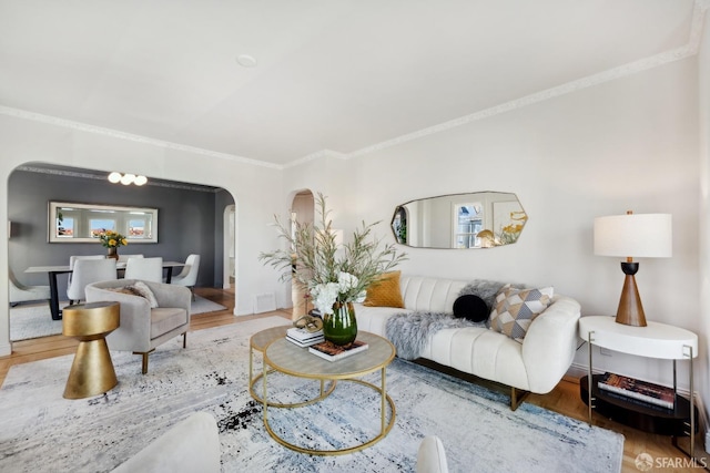 living room featuring arched walkways, wood finished floors, and ornamental molding