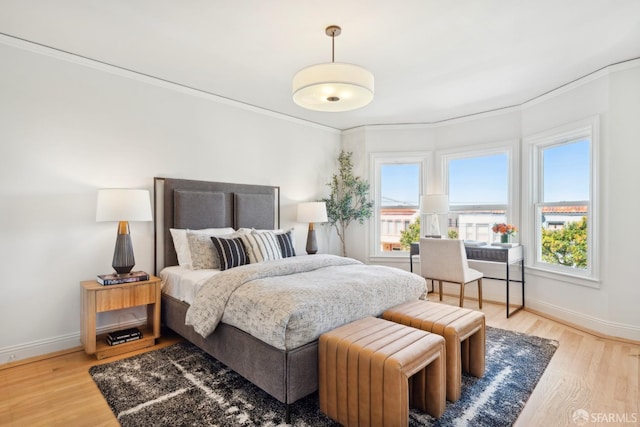 bedroom featuring crown molding, light wood-style floors, and baseboards