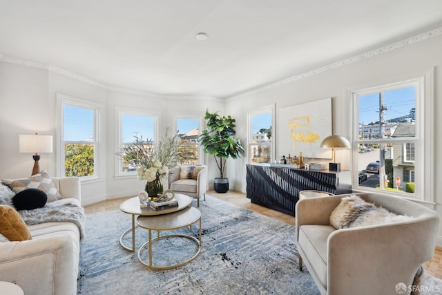 living area with plenty of natural light, wood finished floors, baseboards, and ornamental molding