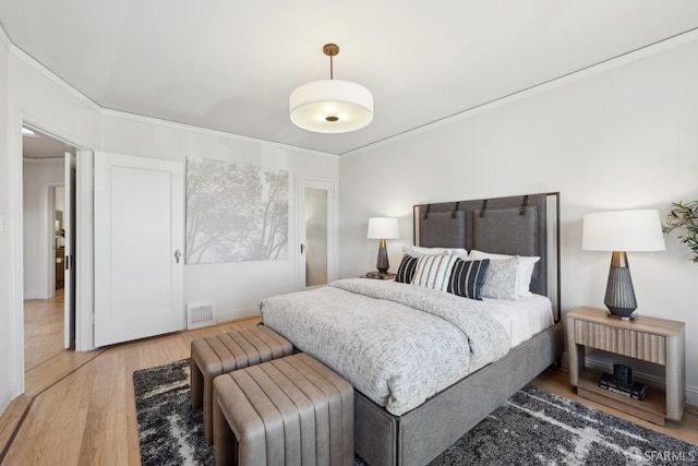 bedroom with light wood finished floors and visible vents