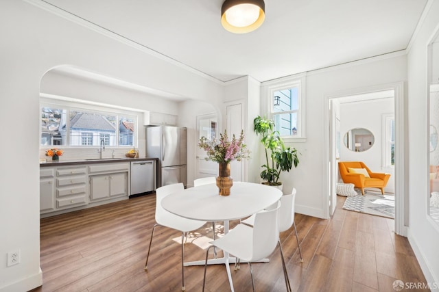 dining area featuring plenty of natural light, crown molding, baseboards, and wood finished floors