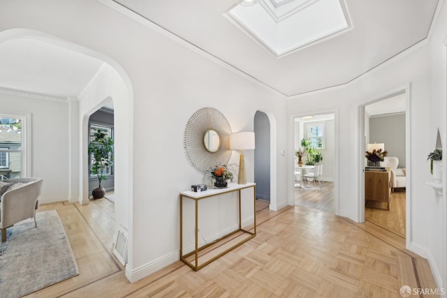 hallway featuring arched walkways, visible vents, baseboards, and ornamental molding