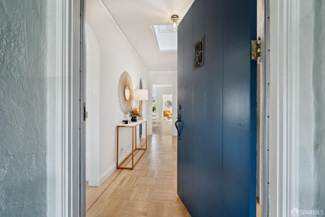 hall featuring baseboards, a skylight, and crown molding