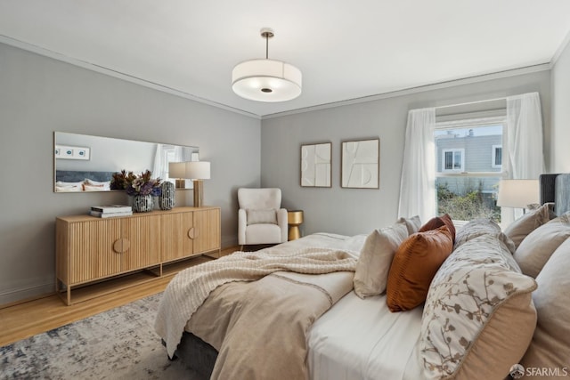 bedroom featuring wood finished floors, baseboards, and ornamental molding