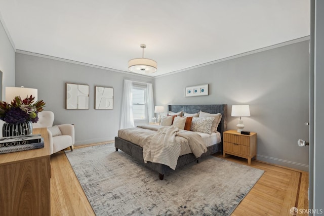 bedroom featuring crown molding, light wood-style floors, and baseboards