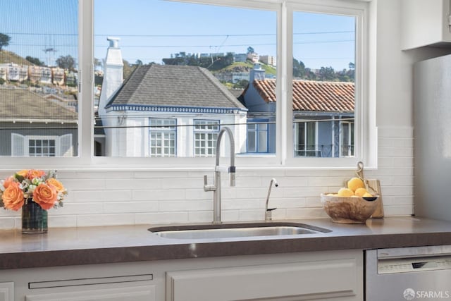 interior space featuring a sink, dark countertops, dishwasher, and white cabinetry