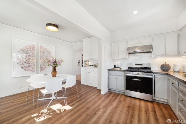 kitchen featuring stainless steel gas stove, under cabinet range hood, backsplash, wood finished floors, and white cabinets