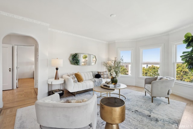 living area with crown molding, plenty of natural light, baseboards, and arched walkways