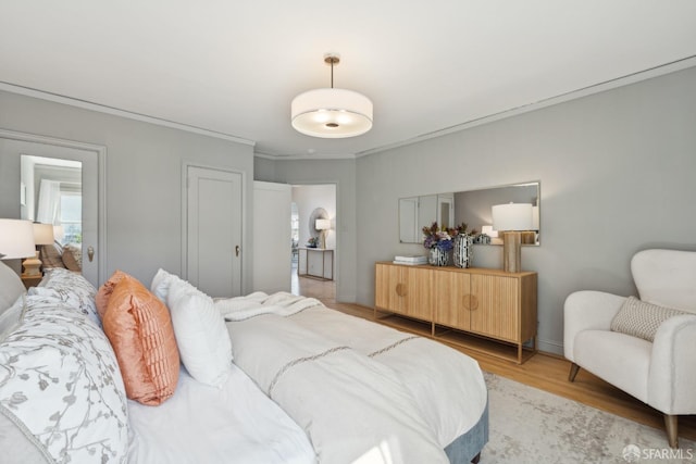 bedroom featuring baseboards, light wood-style floors, and ornamental molding