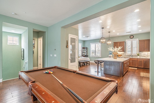 rec room with baseboards, dark wood-type flooring, a sink, and a healthy amount of sunlight