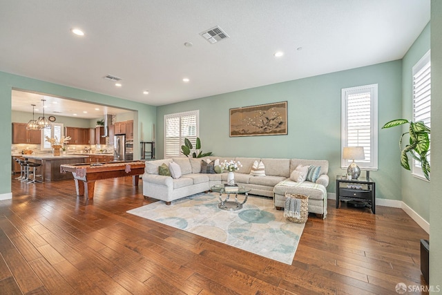 living room with dark wood-style flooring, plenty of natural light, visible vents, and baseboards