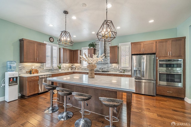 kitchen with tasteful backsplash, a kitchen bar, appliances with stainless steel finishes, and dark wood-type flooring