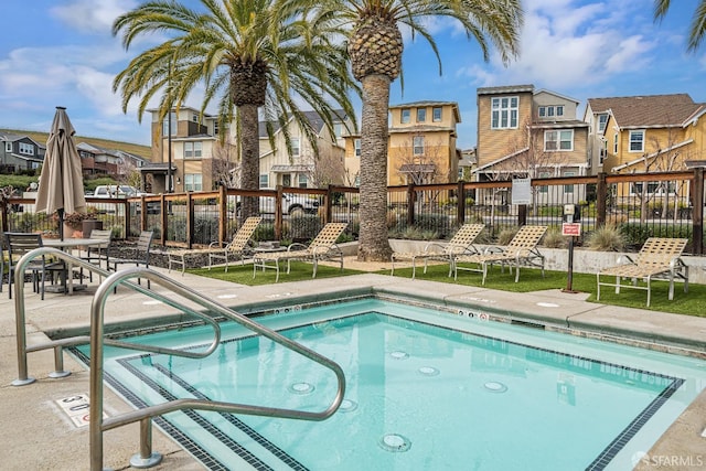 view of swimming pool featuring a hot tub, a residential view, and fence