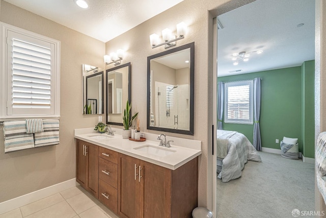 ensuite bathroom with connected bathroom, a sink, visible vents, baseboards, and a shower stall