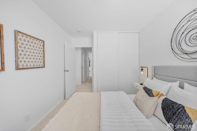 bedroom featuring light colored carpet and a closet