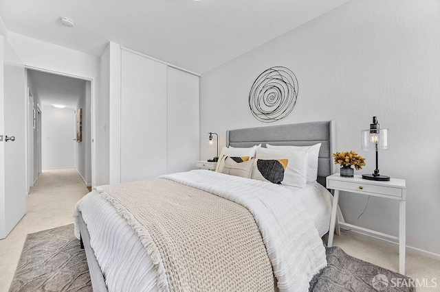 bedroom featuring light colored carpet, a closet, and baseboards