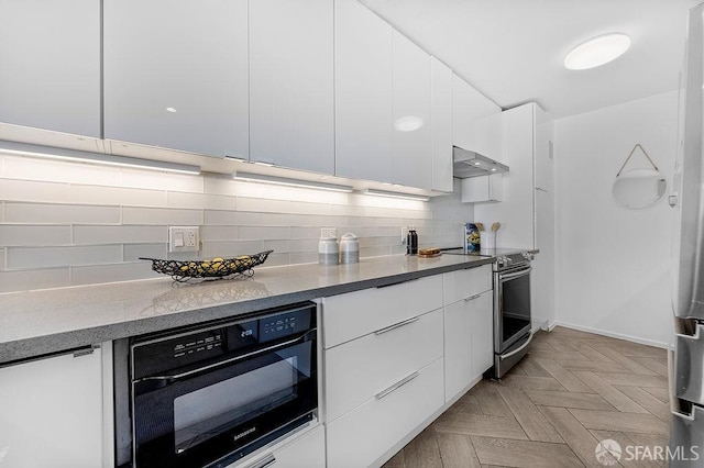 kitchen with modern cabinets, stainless steel range with electric cooktop, white cabinets, tasteful backsplash, and wall oven