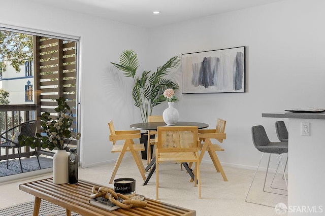 dining room featuring light colored carpet and baseboards