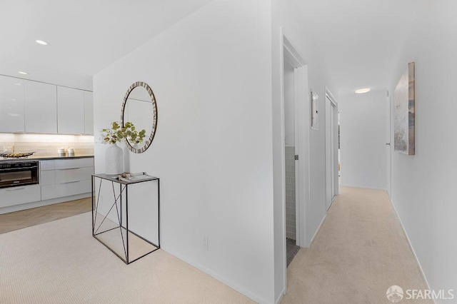 hallway with light colored carpet, recessed lighting, and baseboards