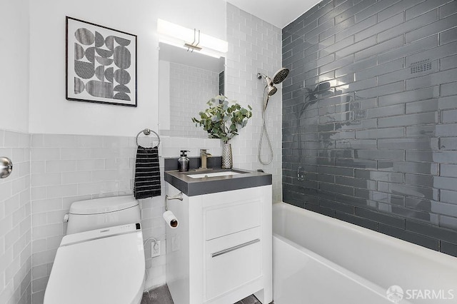 full bathroom with tile walls, washtub / shower combination, toilet, and vanity